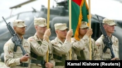 Кабулдан солтүстікке қарай орналасқан Баграм әскери әуе базасында өткен шара кезінде АҚШ пен Ауғанстан туларын ұстап тұрған америкалық сарбаздар. 27 мамыр 2003 ж.