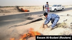 IRAQ - Iraqi policemen threw sand to put out tyres that the protesters had set ablaze during a protest at the main entrance to the giant Zubair oilfield near Basra, Iraq July 17, 2018.