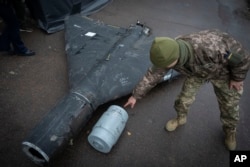 Un militar ucrainean, examinând o dronă rusească Shahed cu bombă termobarică, doborâtă de Ucraina
