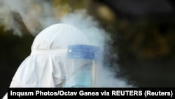 A koronavírus elleni védőfelszerelést és maszkot viselő mentőst fertőtlenítik a bukaresti mentőszolgálat központjánál.