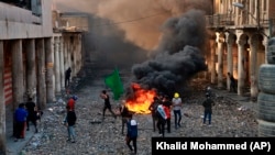 Anti-government protesters start a fire while security forces close Rasheed Street during clashes in Baghdad on November 28.