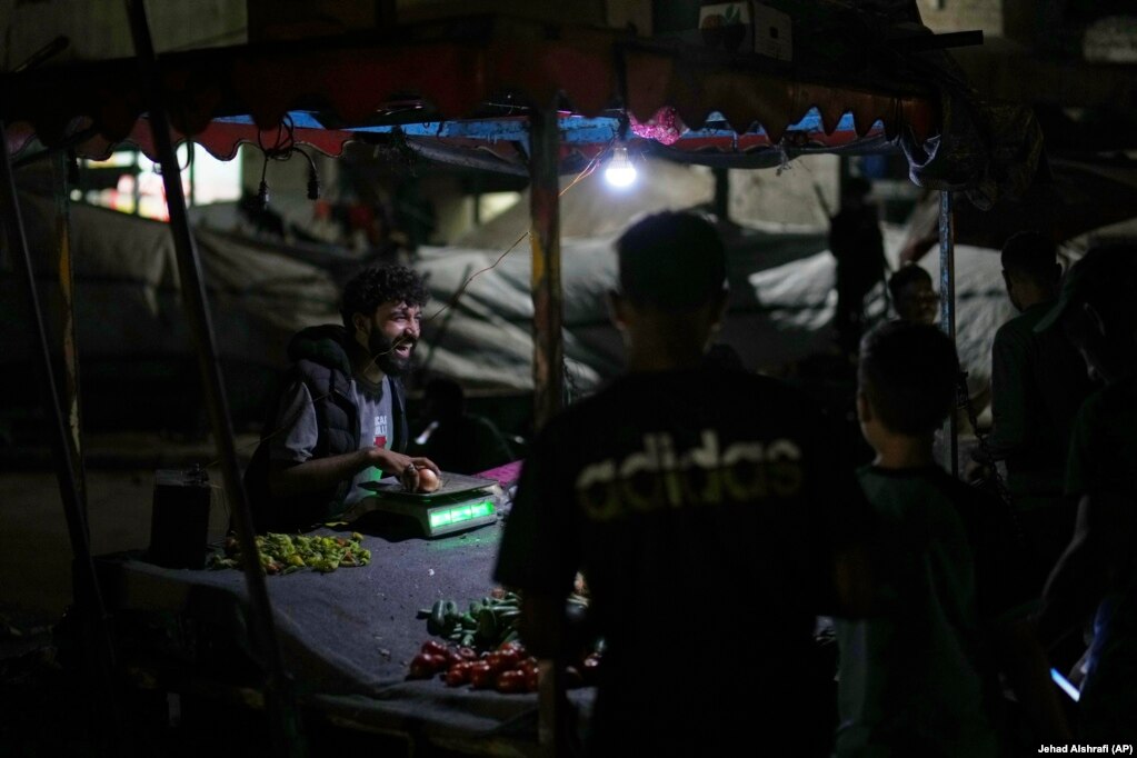 Një shitës ambulant palestinez duke buzëqeshur para konsumatorëve të tij, teksa po shiste perime pranë plazhit, në një kamp për të zhvendosurit në portin e Qytetit të Gazës, më 2 shtator 2025.