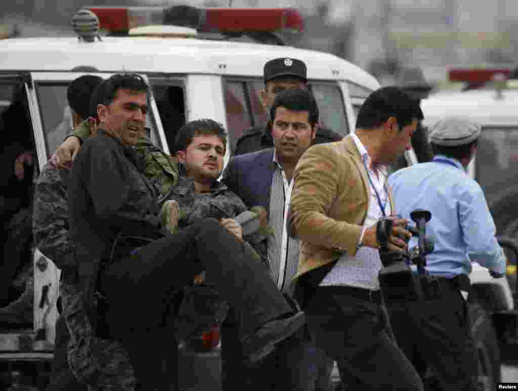 Afghan security forces carry an injured security officer after the attack.