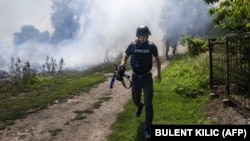 UKRAINE – An AFP journalist runs as smoke rises behind after a bombardment in Bakhmut, Eastern Ukraine, on July 31, 2022