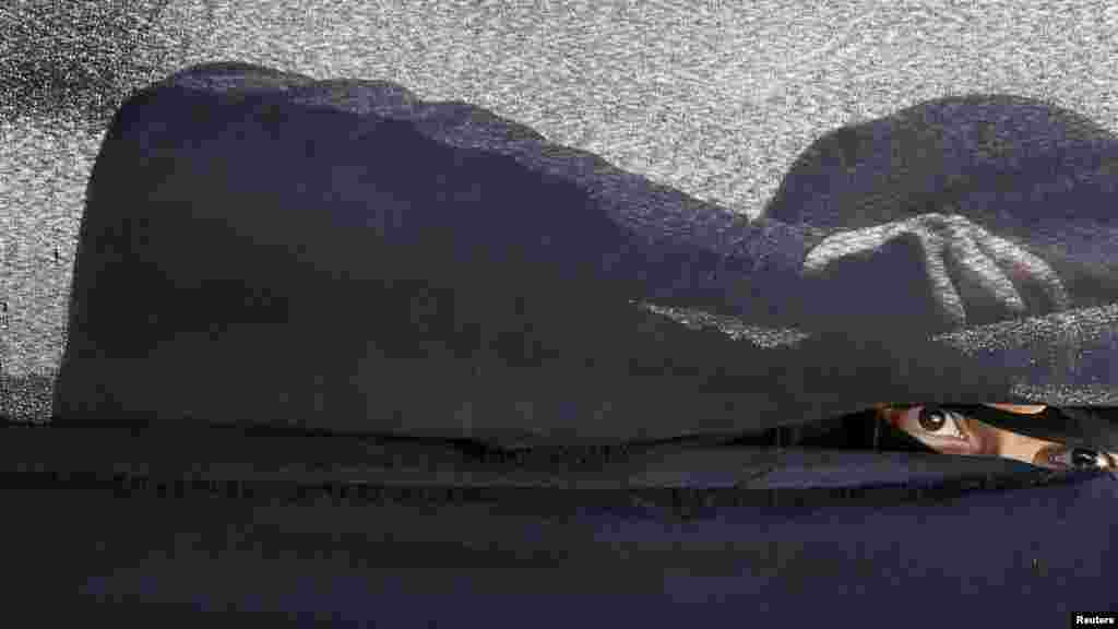 Huti tarapdarlary Saud ýolbaşçylygynda Sanaa urulýan howa zarbalaryna garşy protest bildirýän mahaly çadyrdan seredip duran aýal. 9-njy mart. (Reuters/Khaled Abdullah)