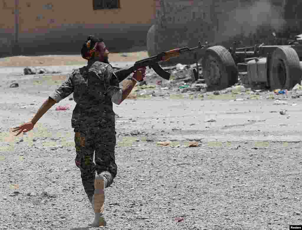 A Syrian Kurdish fighter from the People&#39;s Protection Units (YPG) fires his rifle at Islamic State militants as he runs across a street in Raqqa on July 3. (Reuters/Goran Tomasevic)