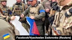 Militari ucraineni distrug steagul rusesc după ce au recucerit un sat din regiunea Harkov, Ucraina, 13 septembrie 2022.