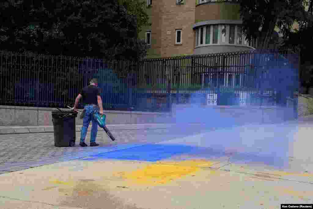 A man cleans up the remnants of Ukrainian colors spread onto the pavement outside the Russian Embassy in Washington D.C. in August 2025.