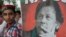 A supporter stands next to a poster of Pakistani cricketer-turned-politician Imran Khan.