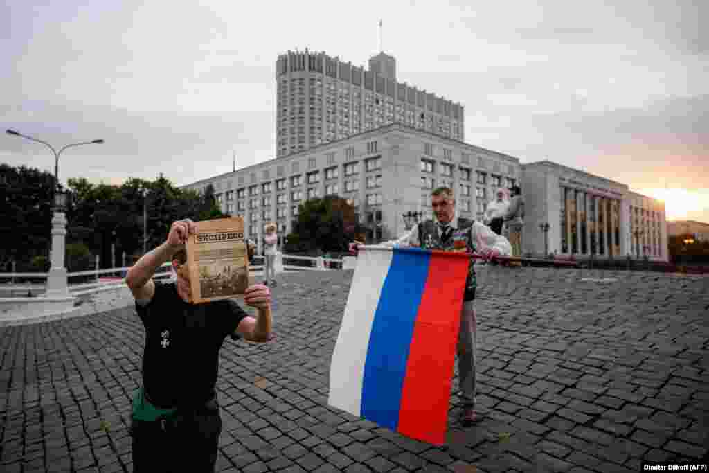 A man holds a Russian flag on the 30th anniversary of the failed August 1991 coup outside the parliament building in Moscow on August 19.&nbsp;