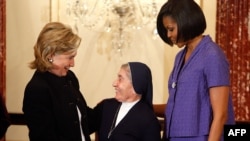 U.S. Secretary of State Hillary Clinton (left) presents the award to Sister Marie Claude Naddaf of Syria as first lady Michelle Obama looks on.