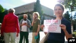 A protester holds a sign reading "Emmanuel Macron: act for homosexuals in Chechnya" during a demonstration in support of gay rights and against homophobia in Chechnya in front of the Russian Embassy in Paris in May 2017.