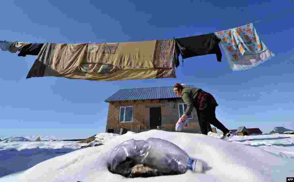 A woman does her laundry in front of her house in Ak-Ordo, a district on the outskirts of the Kyrgyz capital, Bishkek. (AFP/Vyacheslav Oseledko)