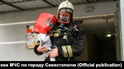 Пожарный выносит ребенка из дома, где возник пожар, 7 октября 2020 года