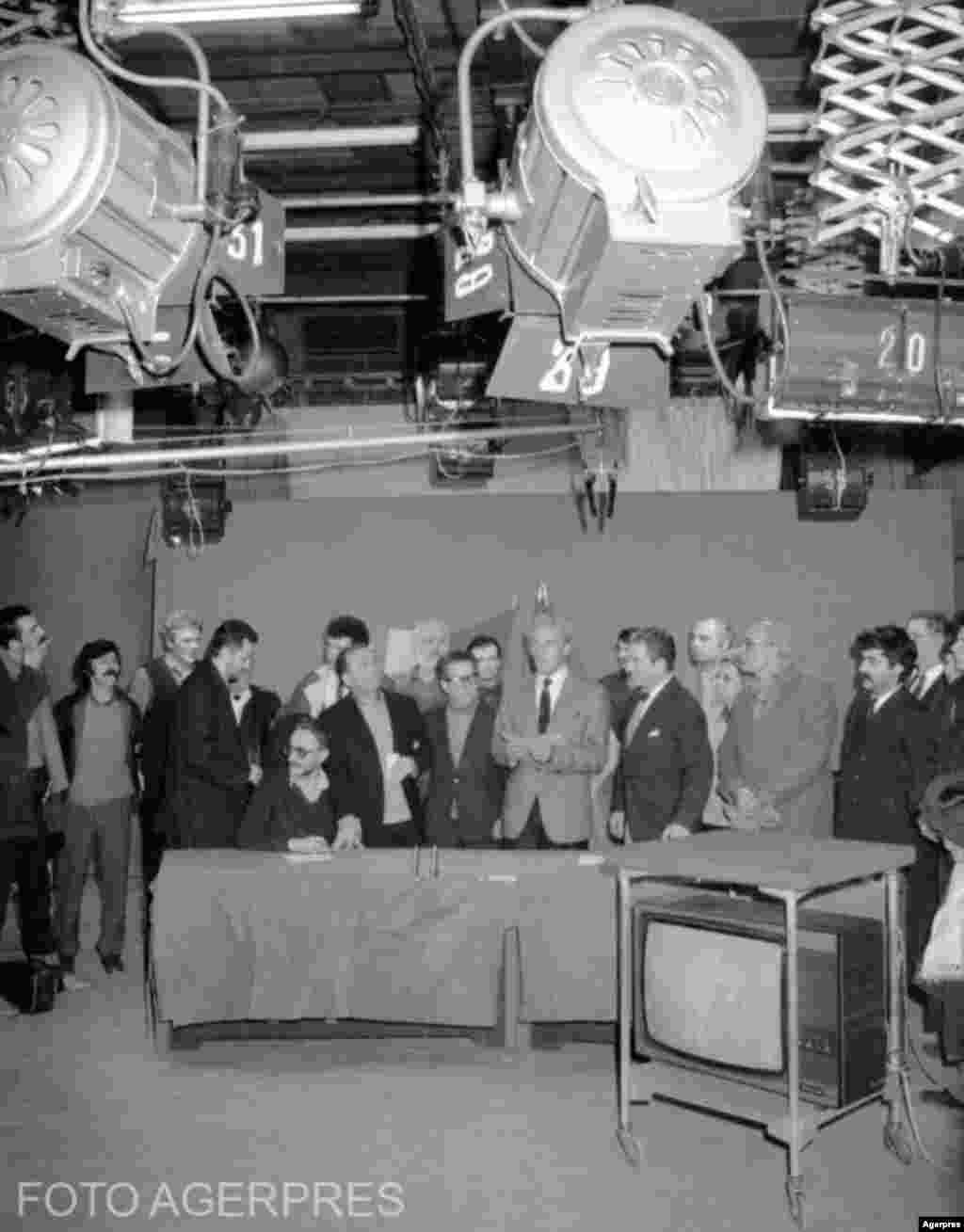 București, 22 decembrie 1989. În direct din studio-ul 4 al TVR, Ion Iliescu, alături de regizorul național-comunist Sergiu Nicolaescu, foarte popular în epocă, și prezentatori și responsabili din TVR