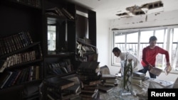 People clean up debris in an apartment damaged after a rocket, fired from Gaza, landed in the southern city of Kiryat Malachi on November 15.