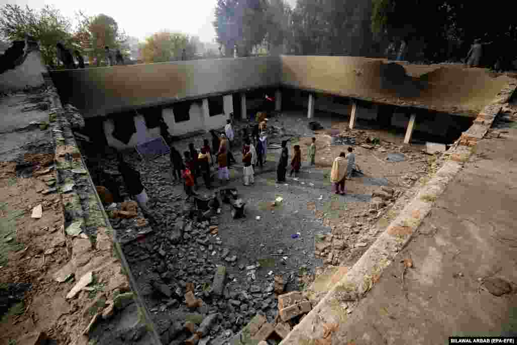 People survey a police station in Charsadda, Pakistan, that was set on fire by a mob after allegations of desecration of the Koran by a suspect.