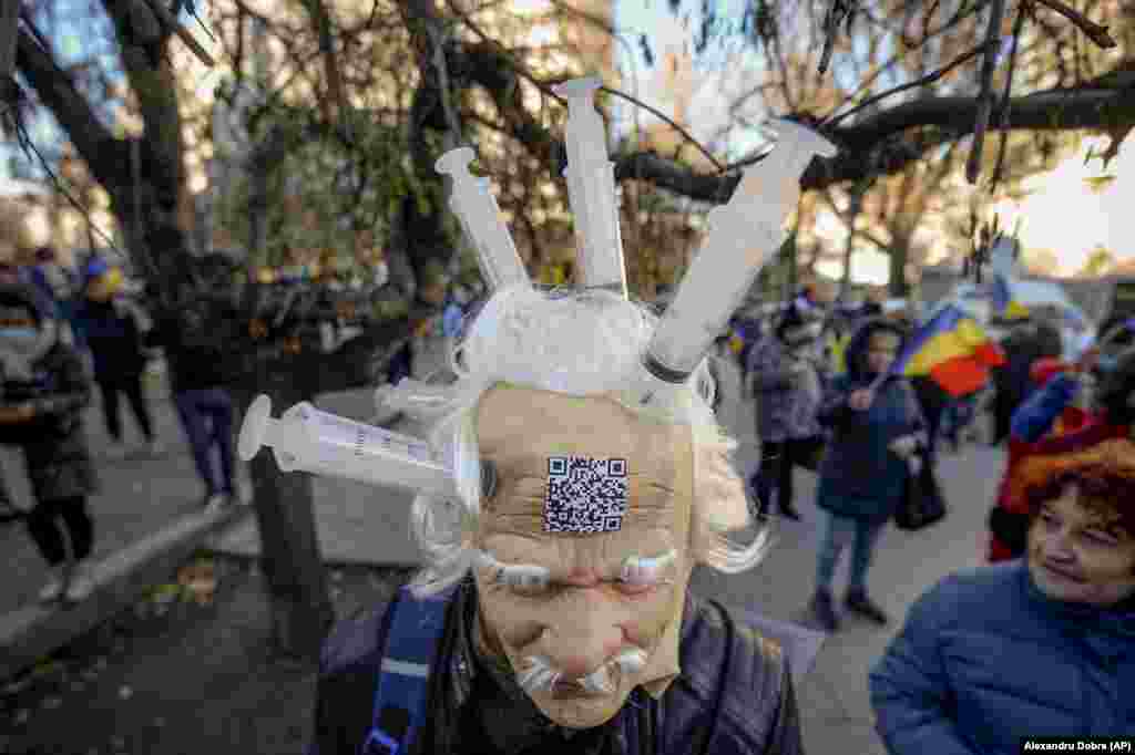 Un bărbat care poartă o mască din latex cu seringi lipite, protestează în București împotriva vaccinărilor, introducerii permisului verde și a restricțiilor legate de COVID-19.