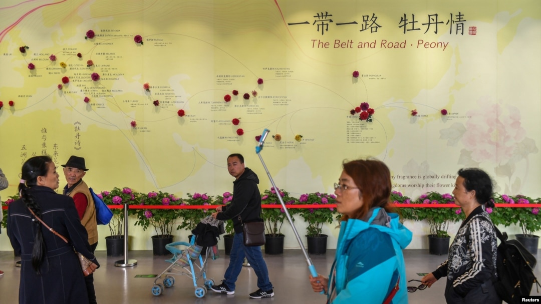 Vizitatorii trec pe lângă un zid cu o hartă care arată speciile de bujor din țările Inițiativei „Belt and Road", la o expoziție horticolă din 2019 din Beijing.