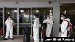 Путешественники носят средства индивидуальной защиты возле международного терминала в аэропорту Сиднея, поскольку страны реагируют на новый вариант коронавируса Omicron на фоне пандемии коронавируса (COVID-19) в Сиднее, Австралия, 29 ноября 2021 года. 