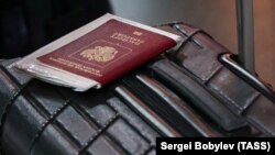 Чемодан и российский паспорт. Иллюстрационное фото