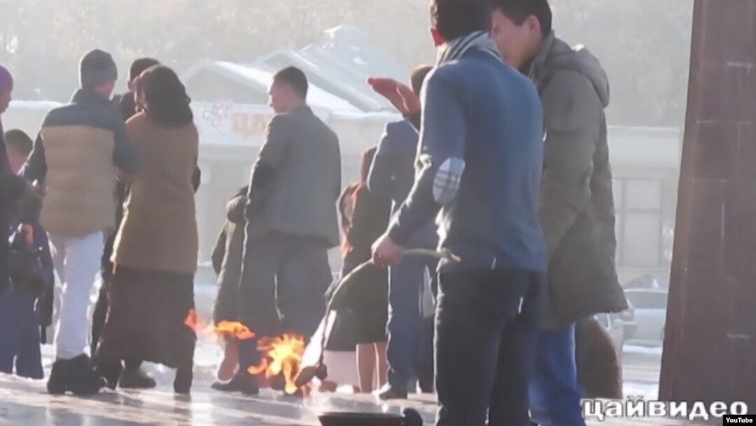 A screengrab from a video circulated on the Internet that appears to show two men in Bishkek roasting potatoes on the eternal flame at the city's memorial to Kyrgyzstan's World War II dead.