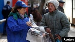 Украина - Женщина раздает бесплатную газету с заголовком на первой полосе «Крым выбрал Россию», Симферополь, 17 марта 2014 г.