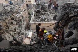 Medici palestinieni caută printre dărâmături în urma atacurilor israeliene asupra unor apartamente de pe strada Yarmuk din orașul Gaza, 24 aprilie 2025.