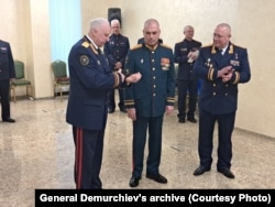 დემურჩიევი (ცენტრში) იღებს ჯილდოს საგამოძიებო კომიტეტის თავმჯდომარის, ალექსანდრ ბასტრიკინისგან, 2024 წლის თებერვალი