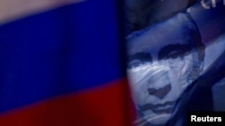 A Russian flag decorated with a portrait of Vladimir Putin flies during a pro-Putin rally in central Moscow.