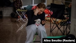 Жінка ховається всередині станції метро зі своїм собакою під час російського удару у Києві, Україна, 29 червня 2025 року.