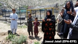 Anisa Mangal (C), the mother of late Afghan female journalist and political advisor Mena Mangal grieves on her grave on May 12.