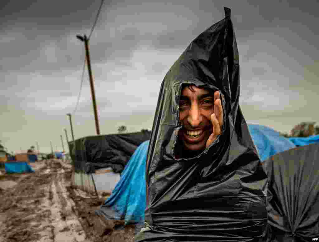 A man protects himself from the rain with a plastic trash bag in the &quot;New Jungle&quot; migrant camp in Calais, France. (AFP/Philippe Huguen)