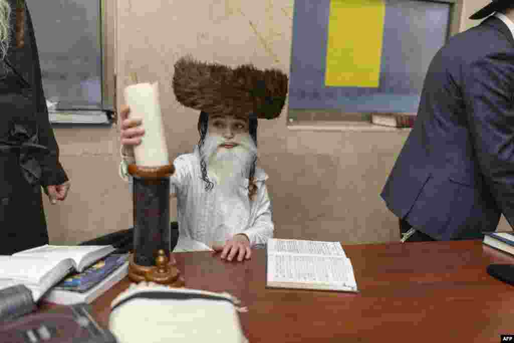Un copil evreu ultraortodox stă într-o yeshiva (școală religioasă) în timp ce sărbătorește Purimul, la Bnei-Brak, pe 2 martie 2026.