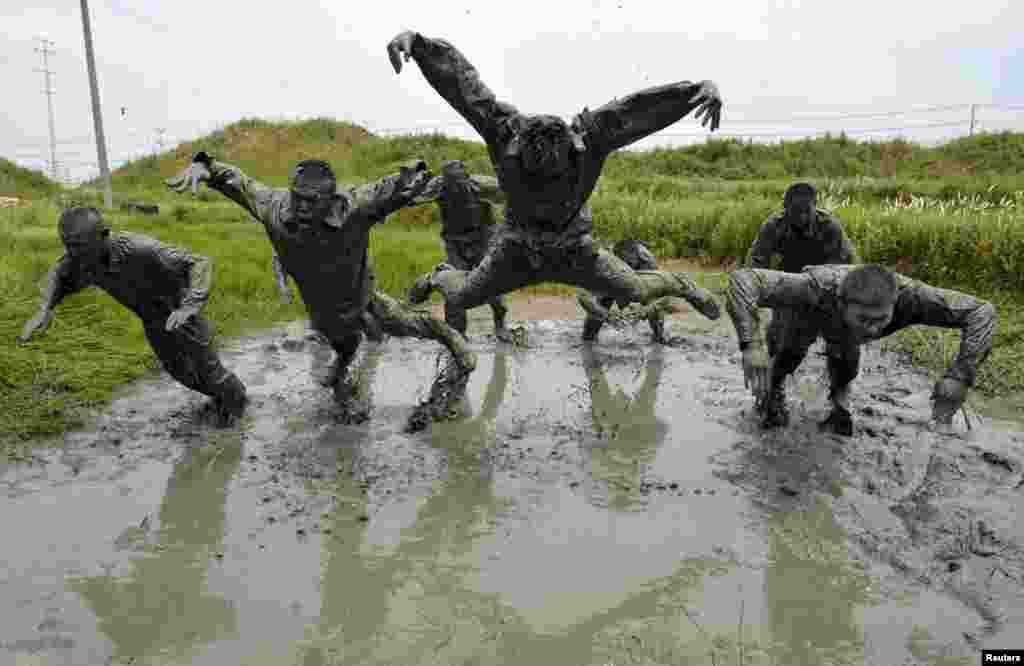 Paramilitary policemen jump over muddy water during a training session at a military base in Chuzhou, Anhui Province, China. (Reuters/China Daily)