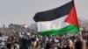 Një person duke valëvitur një flamur palestinez gjatë zhvendosjes së njerëzve në veriun e Rripit të Gazës. Fotografi nga arkivi.