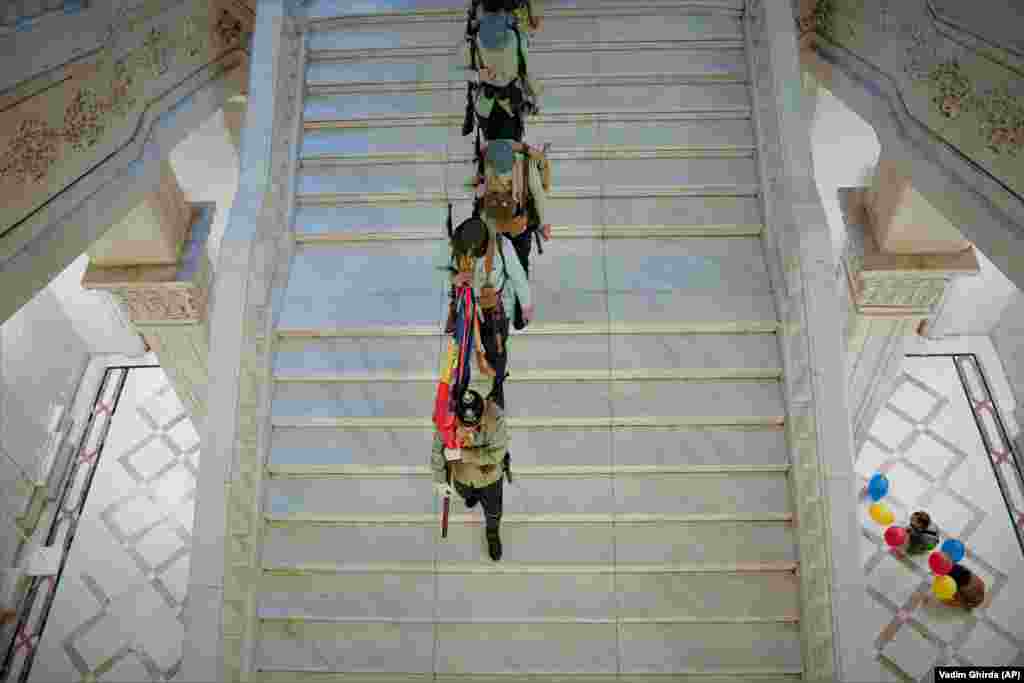 Мужчины в старинной военной форме идут по лестнице Дворца Парламента (Дома Народа) &ndash; второго по величине административного здания в мире после Пентагона, Бухарест, Румыния