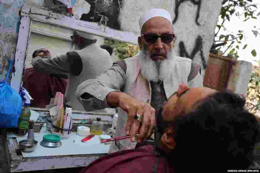 A barber shaves a customer&#39;s beard at a roadside shop during World AIDS Day in Peshawar, Pakistan.&nbsp;According to doctors, cuts from razor blades that haven&#39;t undergone proper sterilization are among the main causes of the spread of AIDS. World AIDS Day, observed annually on December 1, is dedicated to raising awareness against the spread of AIDS and HIV infections.