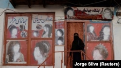 A woman wearing a niqab enters a beauty salon where the ads of women have been defaced in Kabul.