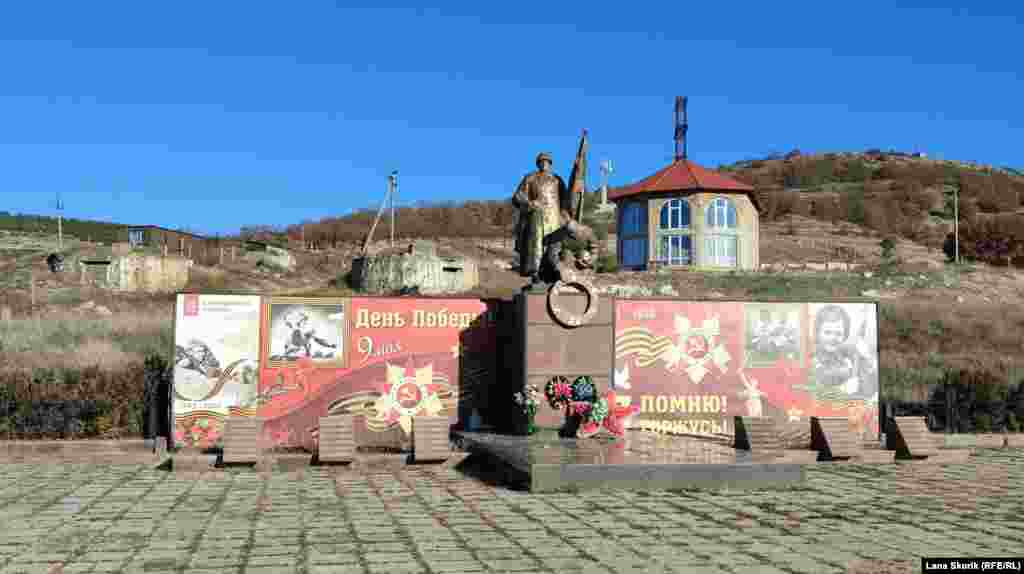 Мемориал на братской могиле воинов и жителей села, павших во Второй мировой войне, на заднем плане слева от памятника &ndash; сооружения двух бетонных ДОТов