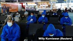 Utasok védőruhában a jakartai repülőtéren 2021. november 29-én.