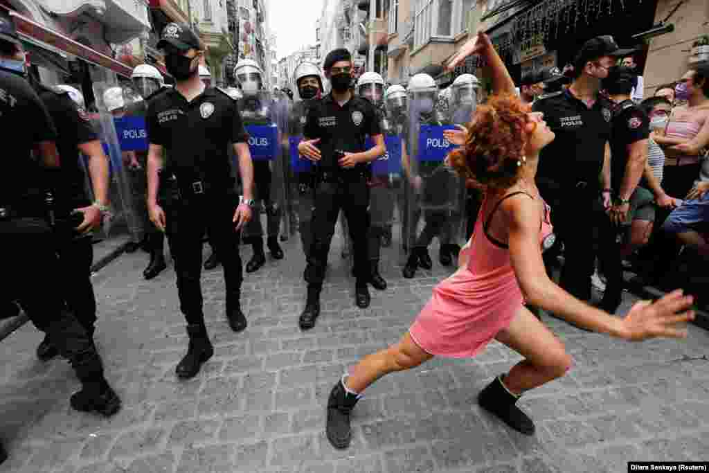 Un manifestant dansează în timp ce polițiștii încearcă să împiedice activiștii pentru drepturile LGBT să se adune la o paradă organizată în centrul orașului Istanbul, Turcia, 26 iunie 2021.