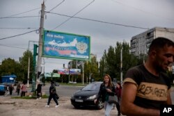 Oamenii merg pe o stradă pe care se află un panou cu mesajul „Alegerea noastră - Rusia”, în Luhansk, pe care Rusia o consideră „Republica Populară Luhansk”, 22 septembrie 2022.