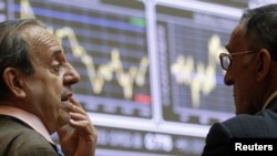 Spanish traders talk near electronic trading boards at the stock exchange in Madrid.