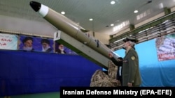 Iranian Defense Minister Amir Hatami stands next to a new Fateh-e Mobin short-range ballistic missile.