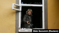 Local resident Valentyna Petrenko looks out of a window that was shattered by shock waves following explosions at a Defense Ministry munitions depot in the eastern Chernihiv region on October 9. 