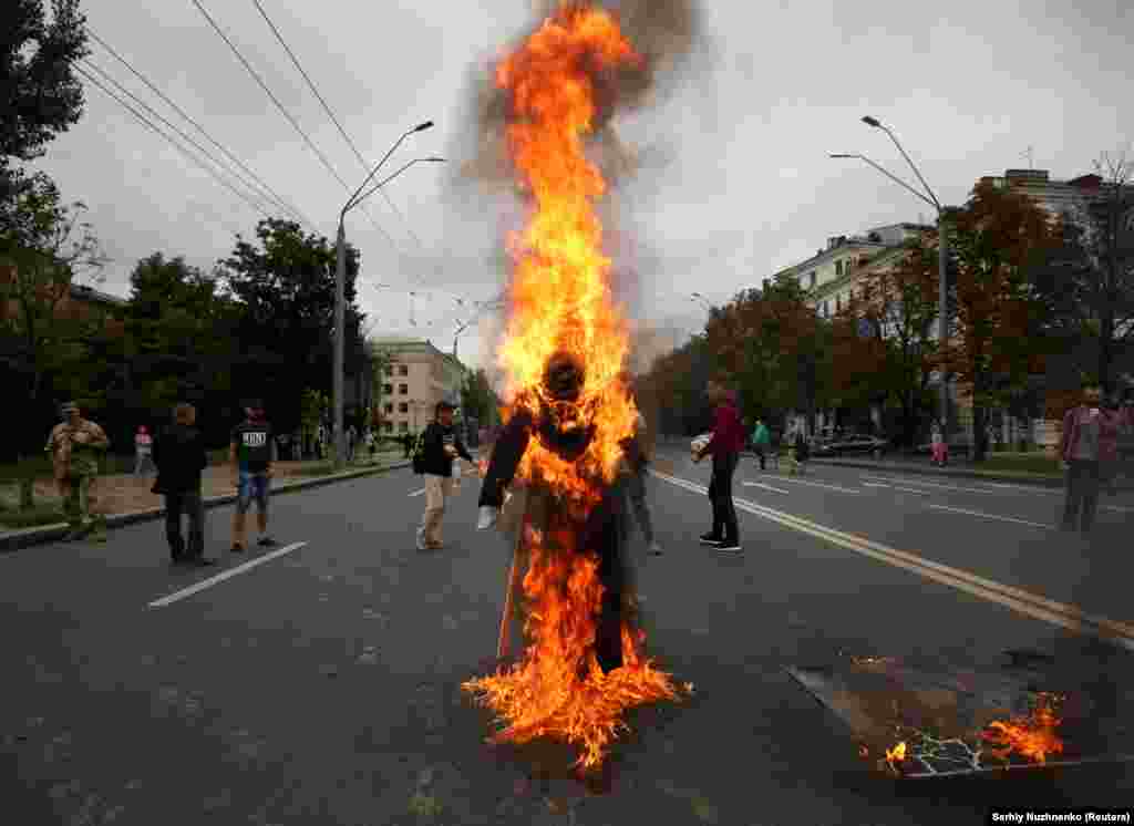 Demonstrators burn an effigy depicting Russian President Vladimir Putin during a rally to commemorate the fourth anniversary of the bloody battle in the eastern city of Ilovaisk, in front of the Russian Embassy in Kyiv. (Reuters/Serhii Nuzhnenko)