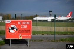 На цій фотографії зображений знак з написом «Заборонена зона для дронів». Позаду приземляється літак в брюссельському аеропорту «Завентем», 5 листопада 2025 року