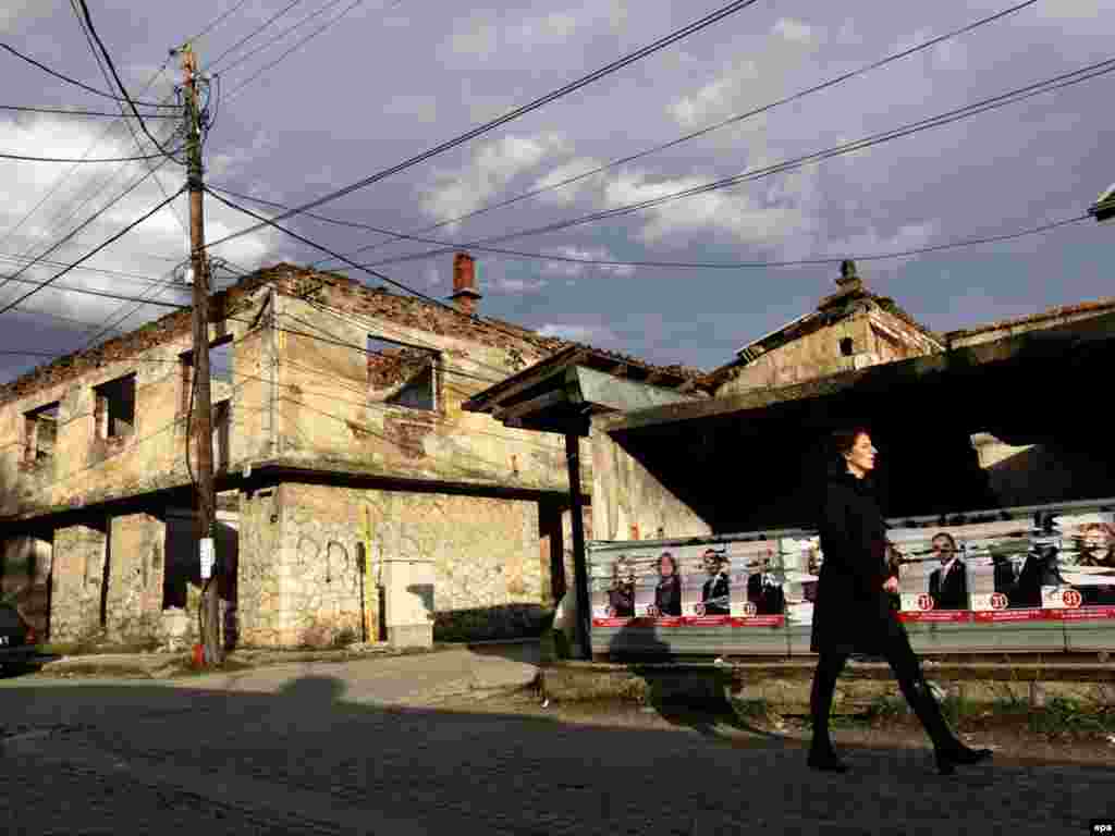 A local resident strides past election posters in Gjakova, Kosovo, ahead of the December 12 vote. Photo by Valdrin Xhemaj for epa