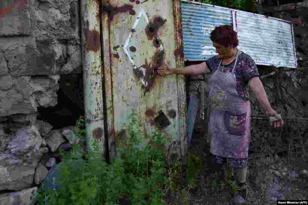 Žena u armenskom selu Aygepar pokazuje kako je kapija njenog dvorišts oštećena granatiranjem.&nbsp;